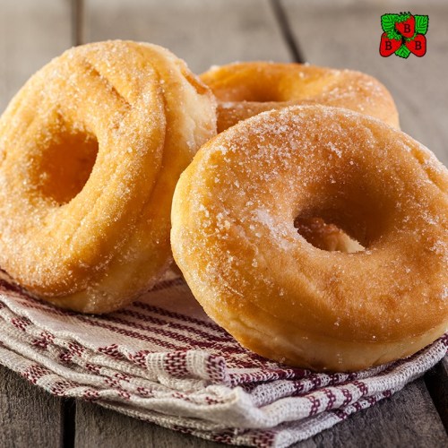 Three sugar-coated donuts on a striped cloth, set against a wooden background.