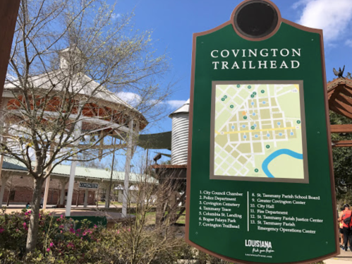 Sign at Covington Trailhead displaying a map and information about local facilities and attractions in Covington, Louisiana.