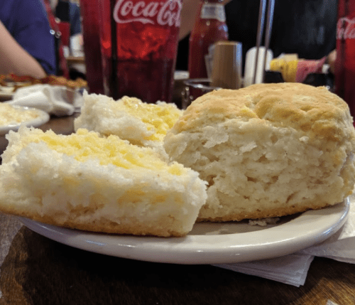 A plate with two fluffy biscuits, one with a golden crust and the other with a soft, white interior.