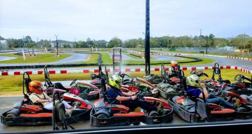 A group of go-karts lined up on a track, with drivers wearing helmets, ready to race in a scenic outdoor setting.