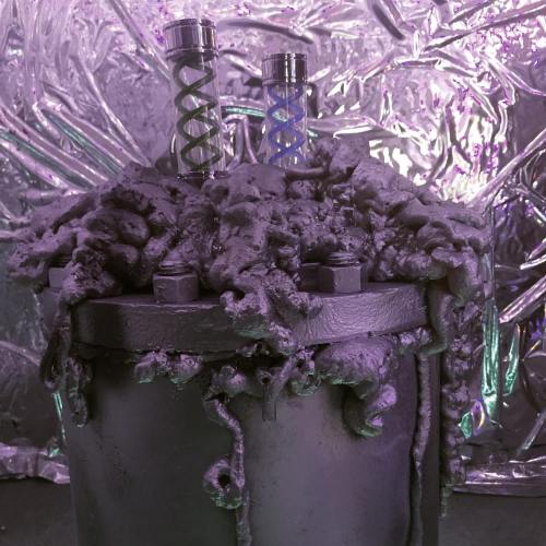 A metallic container covered in purple, textured material, with two glass tubes protruding from the top against a shiny backdrop.