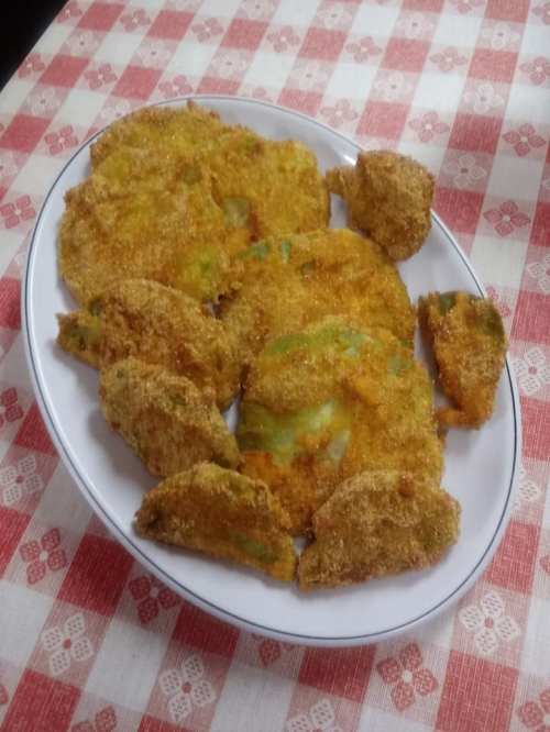 A platter of golden-brown, breaded and fried vegetable fritters on a checkered tablecloth.