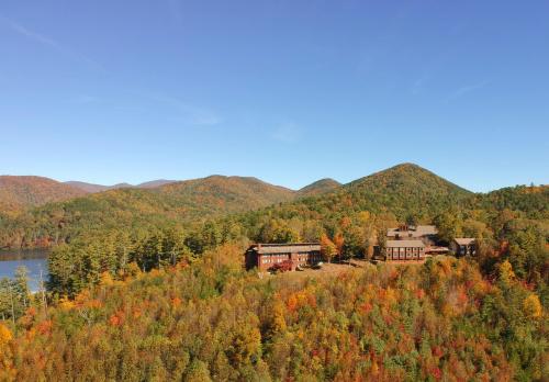 Aerial view of a lodge surrounded by vibrant autumn foliage and mountains under a clear blue sky.