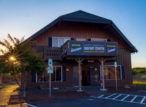 Exterior of the North American Bigfoot Center, featuring a museum and gift shop, with a sunset in the background.