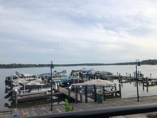A peaceful marina with several boats docked, surrounded by calm water and a cloudy sky.