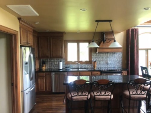 A modern kitchen with wooden cabinets, stainless steel appliances, and a central island with bar stools.