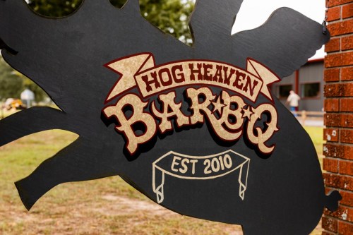 Sign for "Hog Heaven Bar-B-Q," established in 2010, featuring a pig silhouette and decorative lettering.