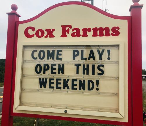 Sign for Cox Farms reads: "Come play! Open this weekend!" with a bright red and white design.