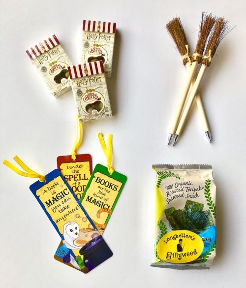 A flat lay of Harry Potter-themed snacks, bookmarks, and a bag of Gillyweed, alongside two broomstick pens.