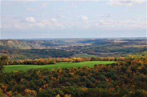 A scenic view of rolling hills and valleys, showcasing vibrant autumn foliage and a clear sky.