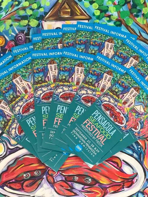 A colorful display of Pensacola Seafood Festival flyers arranged on a vibrant, artistic background.