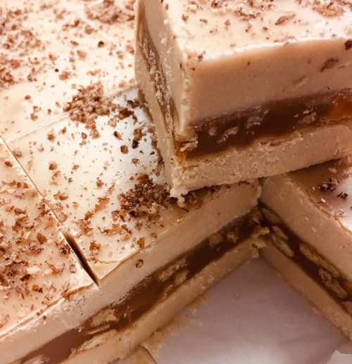Close-up of layered fudge with a creamy top, caramel center, and sprinkled chocolate shavings on top.