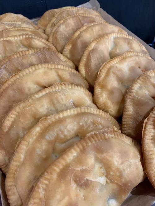 A close-up of a tray filled with golden-brown, flaky pastries arranged in neat rows.
