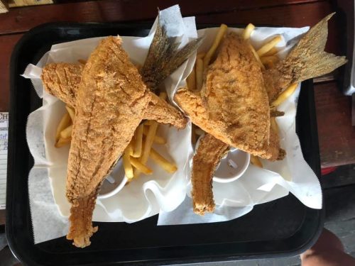 Two fried fish served on a tray with French fries and dipping sauce.
