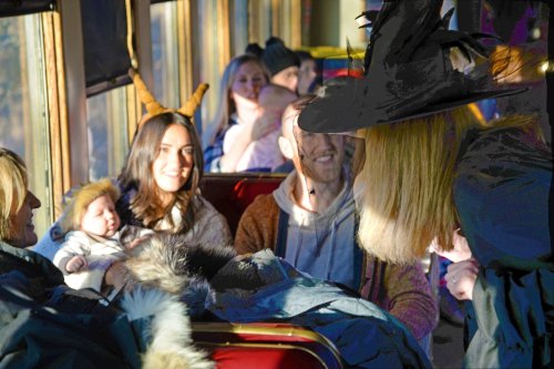 A group of people on a bus, with one woman in a witch hat interacting with others, including a baby.