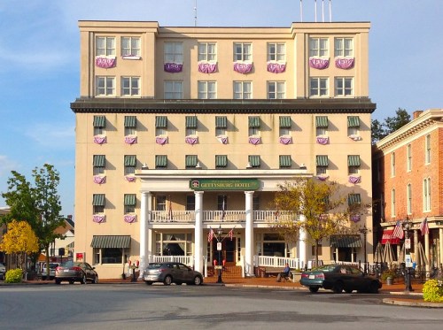 Historic Gettysburg Hotel with green awnings and decorative banners, located in a charming town square.
