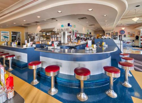 A retro diner interior featuring a curved counter with red stools and a colorful, inviting atmosphere.
