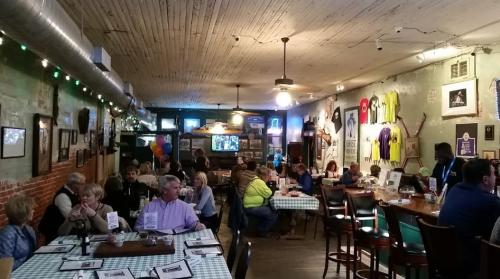 A cozy restaurant interior with patrons dining, checkered tablecloths, and vintage decor on the walls.