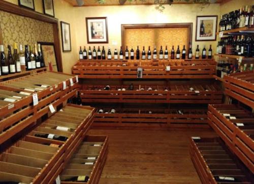 A wine shop interior with wooden racks displaying bottles and several empty crates, creating a cozy atmosphere.