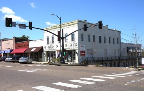 A street view of a small town with shops, traffic lights, and a clear blue sky.