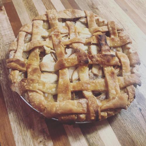 A freshly baked apple pie with a golden lattice crust on a wooden table.