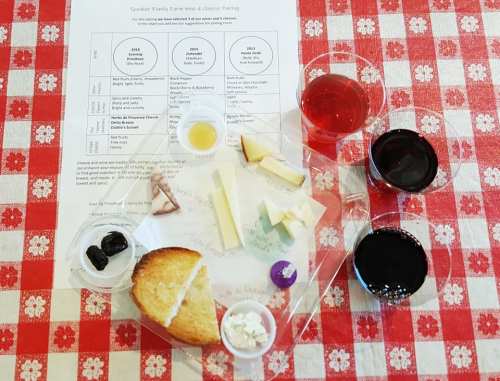 A tasting setup with cheese, bread, and wine samples on a checkered tablecloth, alongside a pairing guide.
