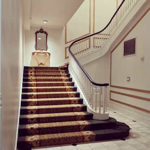 Elegant staircase with a patterned carpet, a decorative mirror, and a console table at the landing.