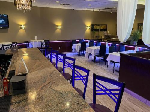 A modern restaurant interior featuring a bar, tables with white linens, and ambient lighting.