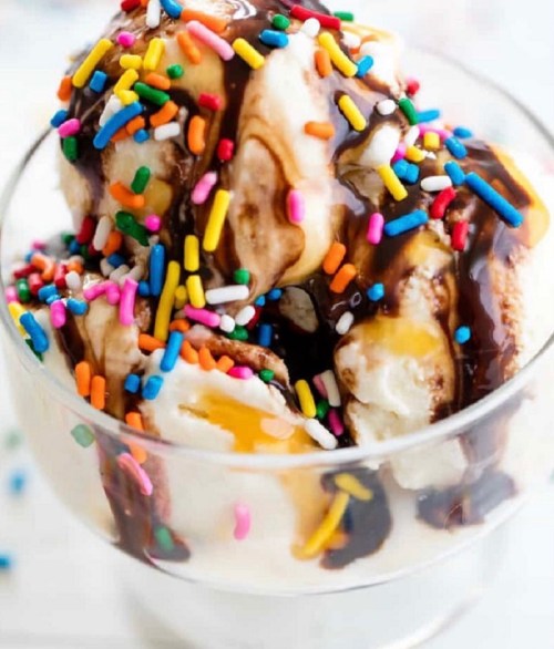 A delicious ice cream sundae topped with chocolate sauce, caramel, and colorful sprinkles in a glass bowl.