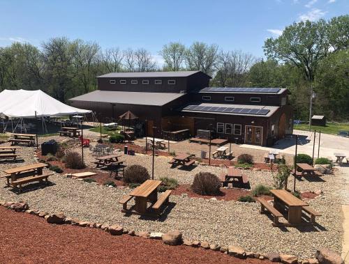A rustic venue with outdoor seating, surrounded by greenery, featuring a large tent and solar panels on the roof.