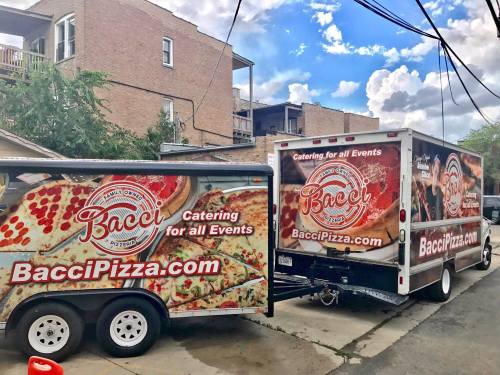 Two food trucks with "Bacci Pizza" branding, parked in an alley, promoting catering services for events.