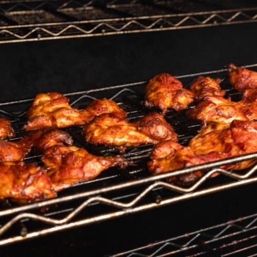 Grilled chicken pieces on a rack, showcasing a smoky, charred appearance.