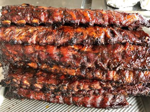 A stack of perfectly cooked, glazed barbecue ribs with a smoky, charred exterior.