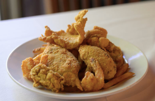 A plate of golden fried fish and shrimp served with crispy fries.