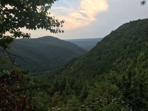 A scenic view of lush green mountains under a cloudy sky, with valleys stretching into the distance.
