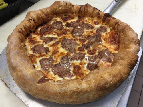 A freshly baked pizza with a thick, golden crust, topped with melted cheese and chunks of sausage.