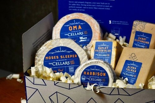 A gift box filled with various artisanal cheeses, including labels for Oma, Moses Sleeper, Harbison, and more.