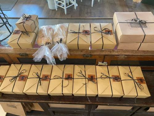 A wooden table displaying neatly packaged boxes and bags tied with black ribbons, ready for distribution.