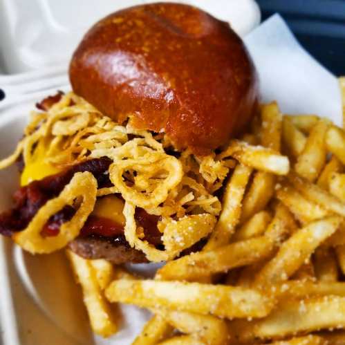 A close-up of a cheeseburger topped with crispy onions, served with a side of golden French fries.