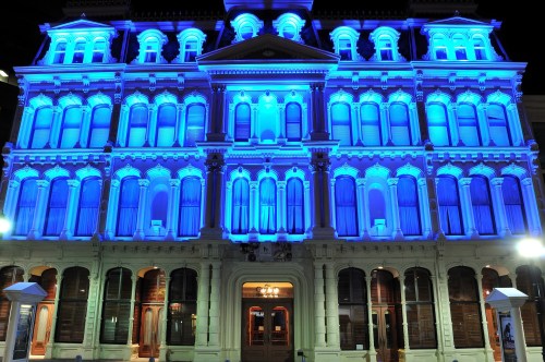 Historic building illuminated in vibrant blue light at night, showcasing its architectural details and grandeur.