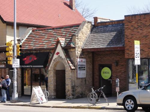 A stone building with a red roof, featuring a pizza restaurant sign and a bicycle parked outside.