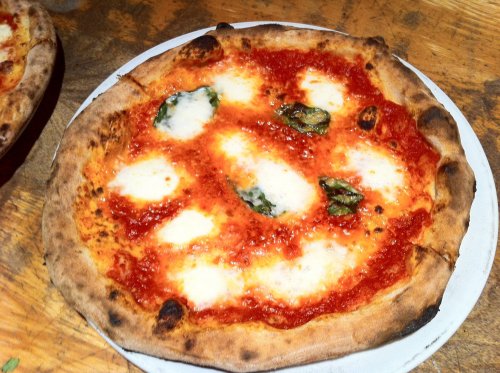 A freshly baked Margherita pizza with melted mozzarella, tomato sauce, and fresh basil on a wooden table.