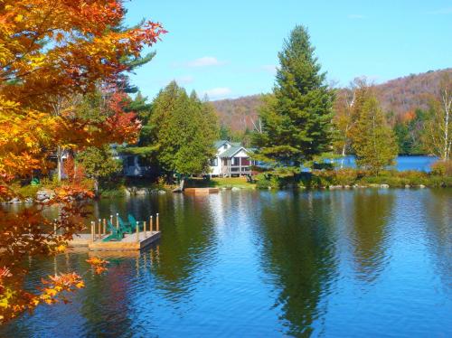 A serene lake scene with a cozy cabin, surrounded by colorful autumn trees and calm water reflecting the sky.