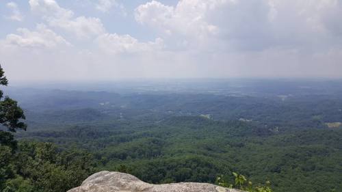 A panoramic view of lush green mountains under a cloudy sky, with valleys stretching into the distance.