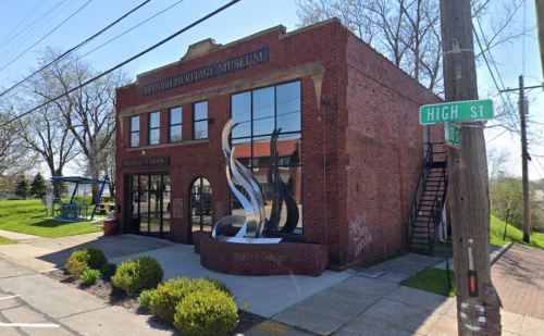 Exterior view of the Lynsch Heritage Museum, featuring a modern sculpture and a corner street sign for High St.