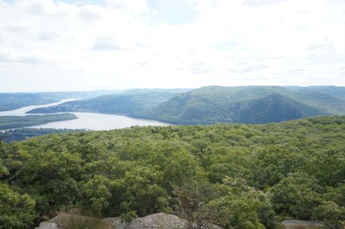 A scenic view of a river winding through green hills under a partly cloudy sky.