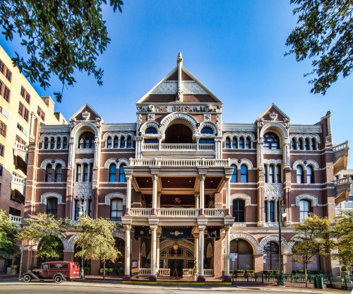 Historic building with ornate architecture, featuring a large porch and decorative details, set against a clear blue sky.