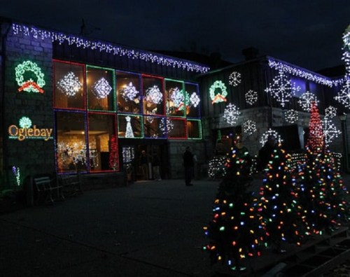 A festive building adorned with colorful Christmas lights and decorations, surrounded by illuminated trees.