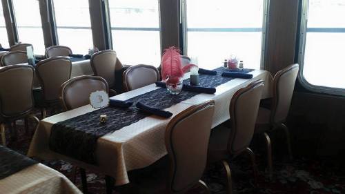 A dining area with elegantly set tables, featuring navy napkins, decorative centerpieces, and a view of the water.
