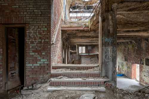 Abandoned building interior with crumbling stairs, exposed brick walls, and graffiti on the walls.